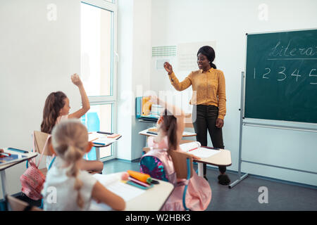 Allieve attive alzando le mani mentre rispondendo alla domanda Foto Stock