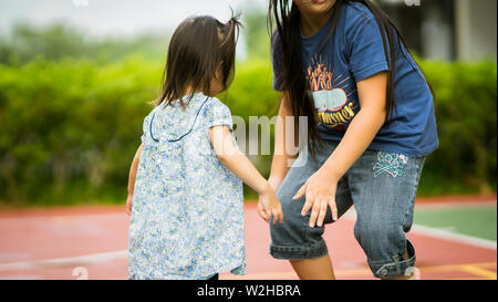 Ragazza asiatica giocando con la sorella nel parco. Foto Stock