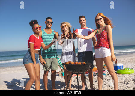 Gruppo di amici di tostatura di bottiglie di birra sulla spiaggia Foto Stock