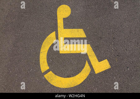 Close up foto di giallo disabilita handicap parcheggio segno disegnato su asfalto di una strada in Caslano, Ticino - Svizzera Foto Stock