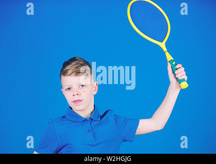 La pratica del tennis abilità. Ragazzo con racket godere di gioco. Futuro campione. Sognare di carriera sportiva. Atleta kid racchetta da tennis su sfondo blu. Tennis Sport e intrattenimento. Bambino a giocare a tennis. Foto Stock