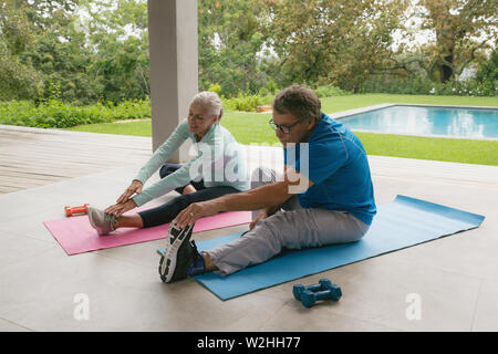 Attivo coppia senior facendo esercizio di stiramento nel portico di casa Foto Stock