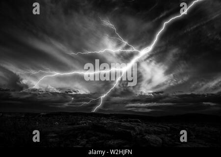 I fulmini colpisce verso il terreno. I fulmini durante un temporale di notte. Immagine in bianco e nero Foto Stock