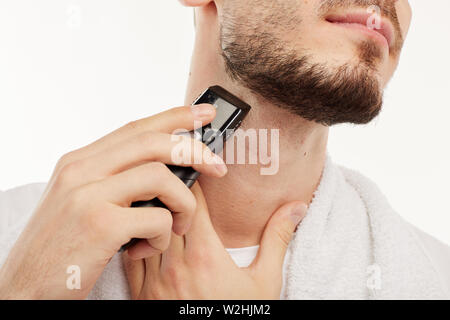 Giovane uomo barbuto rivestimenti proprio in barba a close up shot. Foto Stock