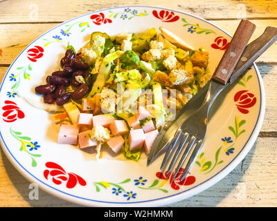 Insalata di verdure con salsiccia e fagioli in piastra sul vecchio tavolo in legno. Foto Stock