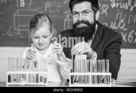 Spiegare la chimica a kid. Come interesse lo studio di bambini. Affascinante lezione di chimica. Uomo Barbuto maestro e allievo con provette in aula. Lezione privata. Scuola di esperimento di chimica. Foto Stock