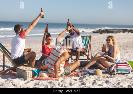 Gruppo di amici la tostatura bicchieri di birra sulla spiaggia Foto Stock