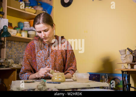 Donna potter rendendo souvenir di ceramica penny whistle nel laboratorio di ceramica Foto Stock