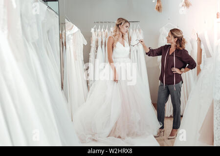 Personalizzare dando giovane donna consigli circa il suo abito. Foto Stock