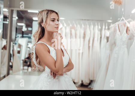 Giovane sposa guardando abiti da sposa in un negozio. Foto Stock