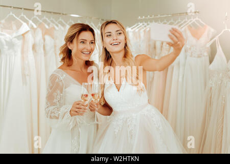 Due felici donne tenendo selfies in abiti da sposa. Foto Stock