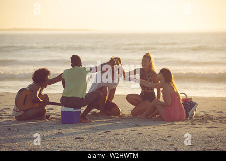 Gruppo di amici di tostatura di bottiglie di birra sulla spiaggia Foto Stock