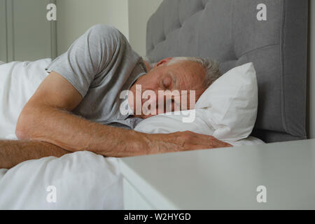 Active senior uomo dorme nel letto in camera da letto Foto Stock