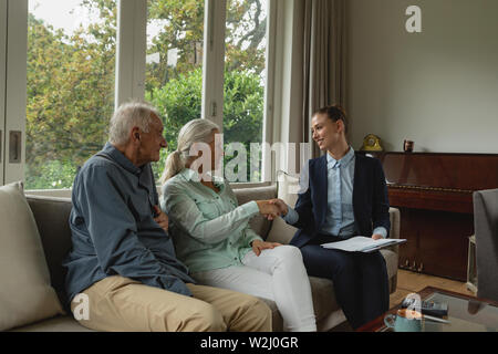 Attiva donna senior stringono le mani con agente immobiliare di soggiorno Foto Stock