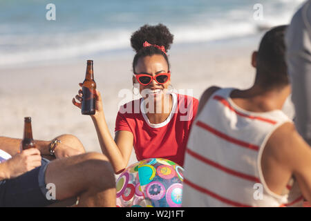 Gruppo di amici avente una birra sulla spiaggia Foto Stock