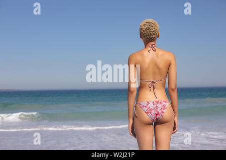 Donna in bikini permanente sulla spiaggia Foto Stock