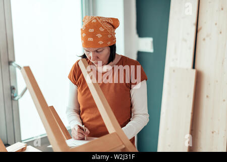 Falegname femmina la riparazione di sedia in legno sedile in small business workshop di falegnameria Foto Stock