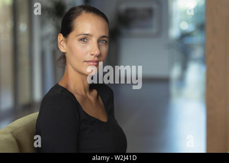 Donna seduta su un divano nella hall all'ospedale Foto Stock