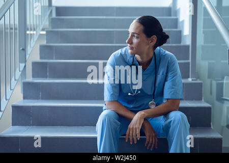 Medico donna seduta sulla scalinata in ospedale Foto Stock