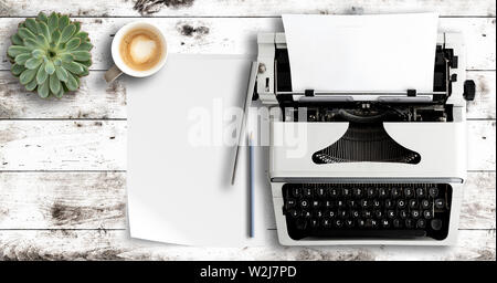 Scatto dall'alto di una macchina da scrivere e carta bianca sul tavolo di legno Foto Stock