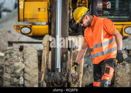 Costruzione di opere di scavo. Escavatore caucasica operatore nel suo 30s. Tema industriale. Foto Stock