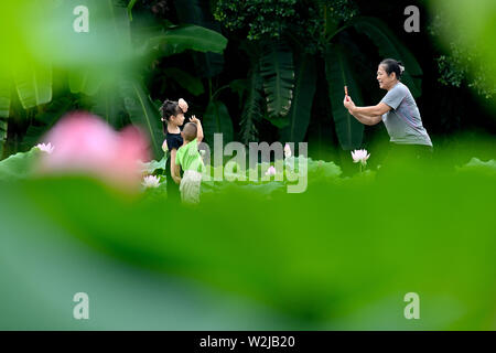 Fuzhou, la Cina della provincia del Fujian. 9 Luglio, 2019. I bambini rappresentano per le foto con i fiori di loto presso il Parco Jinshan in Fuzhou, capitale del sud-est della Cina di provincia del Fujian, Luglio 9, 2019. Credito: Jiang Kehong/Xinhua/Alamy Live News Foto Stock