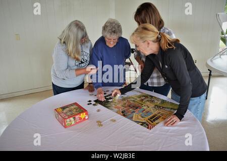 Le donne dalla famiglia reale a raccogliere facendo cruciverba - madre a 90 e 2 figlie e in leggi al barbecue divertirsi insieme Foto Stock