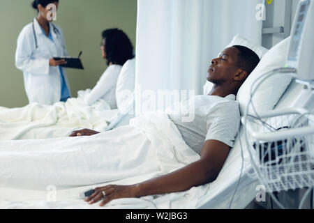 Paziente di sesso maschile dormire nel letto nel reparto di degenza in ospedale Foto Stock