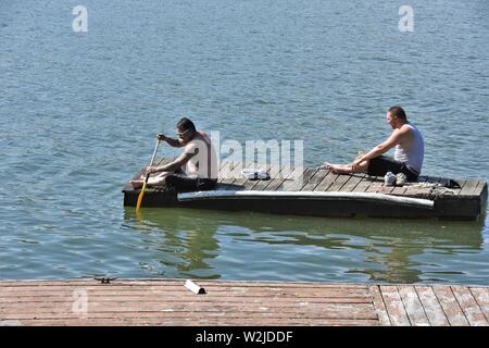 2 Gli uomini paddling recuperati dock torna alla loro casa sul lago in una giornata calda a Clearlake Clear Lake California al salvataggio per la pesca e di vincolare il battello Foto Stock