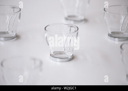 Close up Cappuccino caffè di vetro la tazza con il manico di metallo sul tavolo bianco. spazio copia Foto Stock