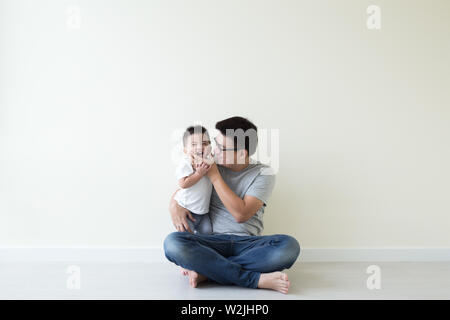 Asian padre e figlio giocando e sorridente sul pavimento in camera, Famiglia divertimento e risate concept Foto Stock