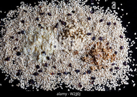 Granola INGREDIENTI Farina di avena fiocchi di mandorle sgusciate Noci e anacardi su sfondo nero direttamente sopra Foto Stock
