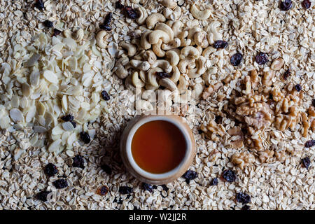Granola INGREDIENTI Farina di avena fiocchi di mandorle sgusciate Noci e anacardi con tazza di miele direttamente al di sopra di Foto Stock
