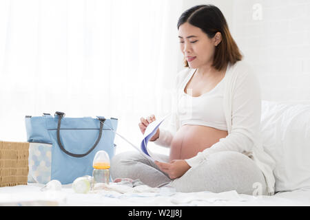 Donna incinta preparazione hospital bag e lista di controllo per la realizzazione di un piano di nascita da un ospedale che ha cure prenatali per la sicurezza del bambino, Pianificazione prena Foto Stock