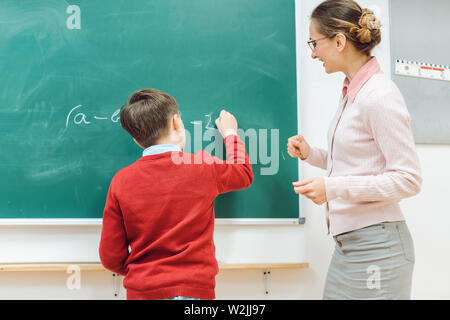 Studente di scuola facendo esercizio alla lavagna Foto Stock