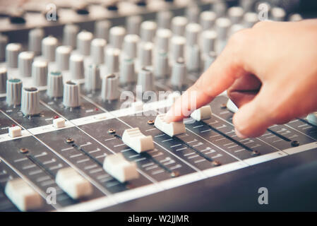 Mani di ingegnere del suono lavora in studio di registrazione il mixer. Esperto la regolazione del volume di una voce, console di miscelazione con scheda mixer. Foto Stock