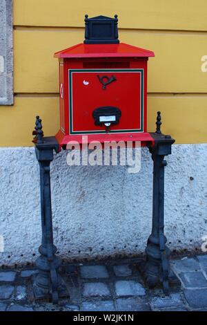 Un tradizionale, rosso, freestanding postbox, sulla strada fuori la 'Posta' (ufficio postale), in Collina del Castello quartiere del Castello di Buda, Budapest, Ungheria. Foto Stock