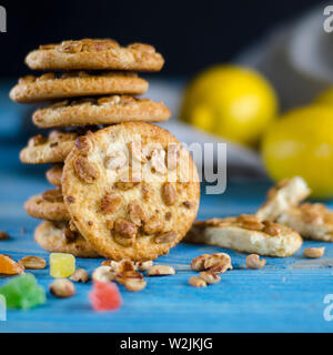 Round orange biscotti con colorati frutti canditi e una fetta di arancia succosa giacente su di un tavolo di legno Foto Stock