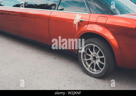 Una vista posteriore di un rosso lungo limousine con una decorazione sul retro della maniglia. La parte posteriore di una festosa limousine rosso all'esterno. Matrimonio di lusso auto Foto Stock