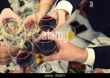 Vista dall'alto del maschio e femmina con le mani piene di bicchieri di vino sopra il ristorante del piano portapaziente. Brindisi e il tintinnio nottolini a cena Foto Stock