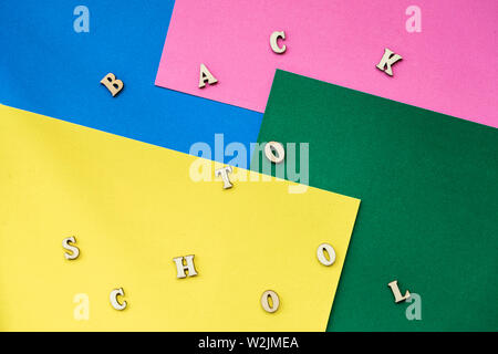 Sfondo colorato con testo. Si torna a scuola, lettere di legno colorate su fogli di carta. Concetto di istruzione, iniziare la scuola, si torna a scuola, vista dall'alto Foto Stock