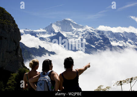 Gli escursionisti femmina godendo della bella vista dalle Schynige Platte, Svizzera: la snow-capped picco della Jungfrau oltre la nebbia-riempito Lauterbrunnental Foto Stock