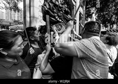 I turisti cinesi Rub la statua del drago per buona fortuna all'entrata di Wong Tai Sin Temple, Hong Kong, Cina Foto Stock