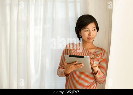 Felice giovane donna utilizzando una tavoletta digitale. Foto Stock