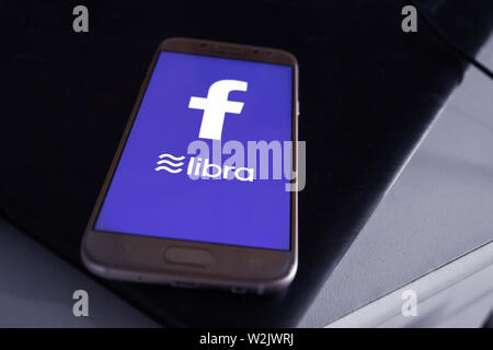 Facebook Cryptocurrency Libra concetto con il cellulare con la bilancia e il logo di Facebook sul bue mobile sullo schermo del telefono Foto Stock