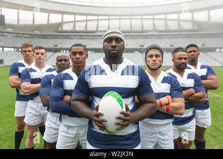 Gruppo di maschi diversi giocatori di rugby assieme con palla da rugby in stadium Foto Stock