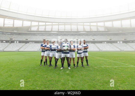 Gruppo di maschi diversi giocatori di rugby assieme con palla da rugby in stadium Foto Stock