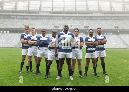 Gruppo di maschi diversi giocatori di rugby assieme con palla da rugby in stadium Foto Stock