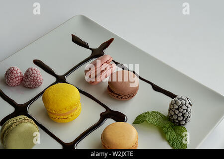 Macarons accompagnato da crema di cioccolato, more, lamponi e foglie di menta Foto Stock