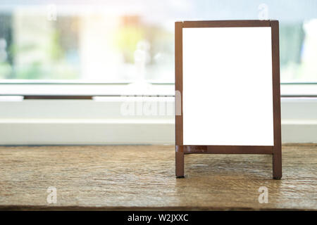 Mock up blank pubblicità lavagna con cavalletto in piedi sulla tavola di legno in cafe e bar ristorante per il display o il montaggio di spazio di progettazione per il testo. Foto Stock
